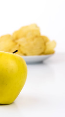 Fototapeta na wymiar yellow apple vs yellow salty potato chips