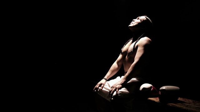 Native American athlete sits on a bench and takes a breath. Wide shot. 