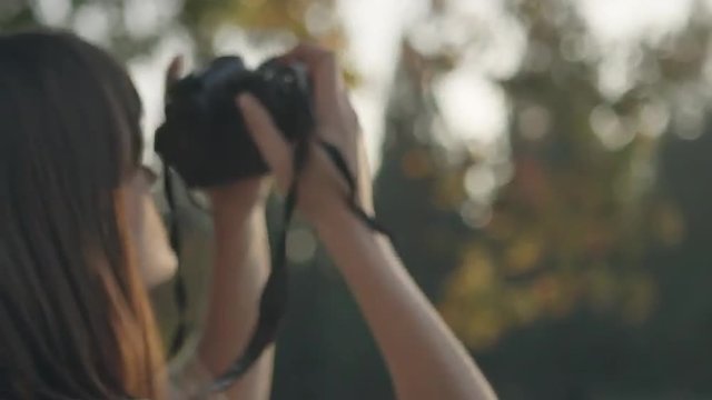 Close up of a young woman taking pictures at sunset