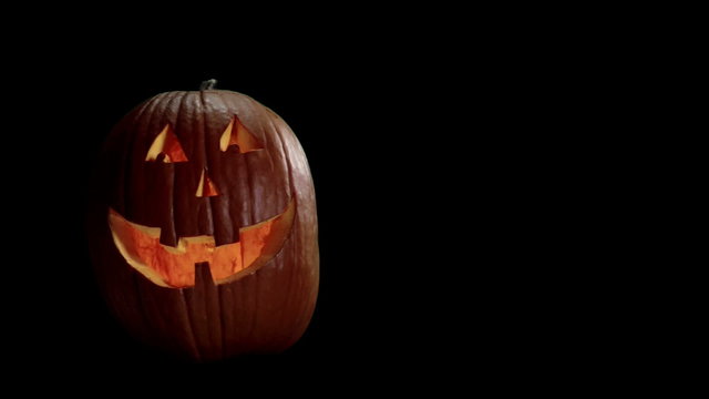 A Jack-o-lantern with a smiling face flickers on a black background