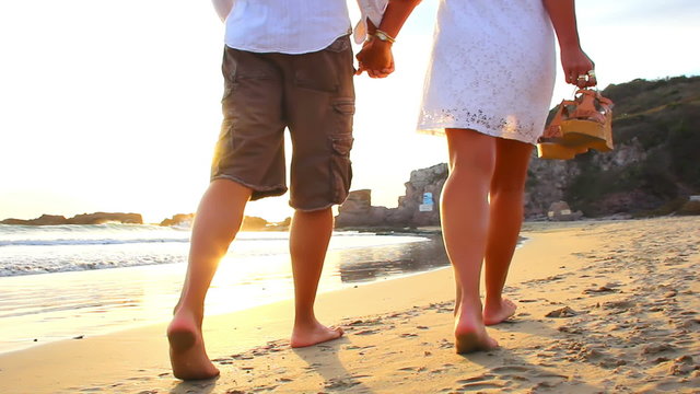 A older couple walk the beach barefoot in Mexico during sunset