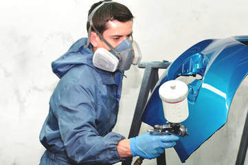 Worker painting blue bumper.