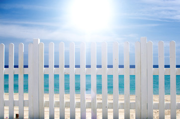 white fence on the beach with blue sea