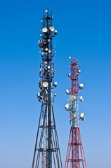 Two telecommunication antennas on a background of blue sky.