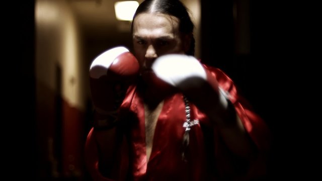 An older Native American boxer shadow boxing in his robe