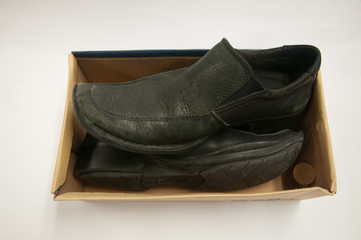 Old pair of black male shoes in box isolated on white