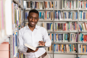 Happy Male Student With Book In Library