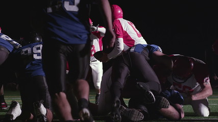 A football player gets tackled as he tries to jump over the pile for a touchdown