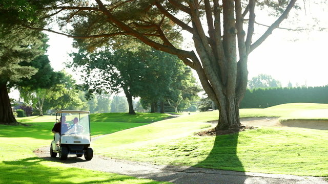 A golf cart comes around the corner on the golf cart path during a sunny day