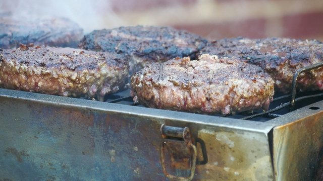 Close Up Of Four Grilling Hamburgers