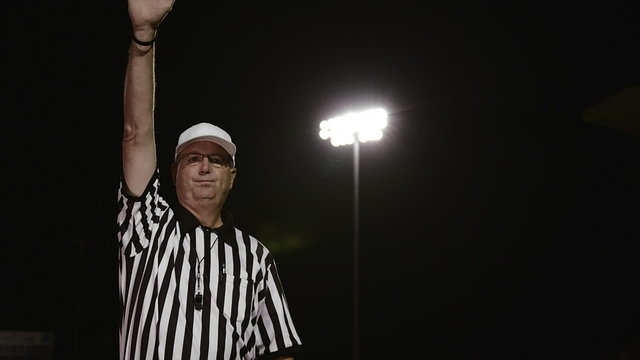 A football referee gives a false start hand signal
