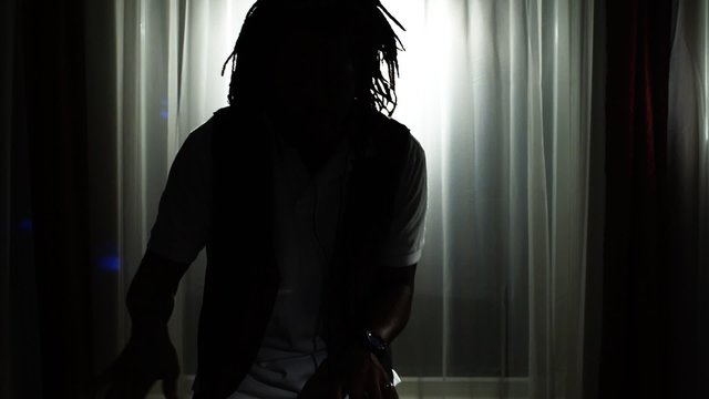 DJ spins records at house party in silhouette. Zoom in