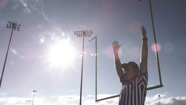 A football referee raises hands over his head for a field goal