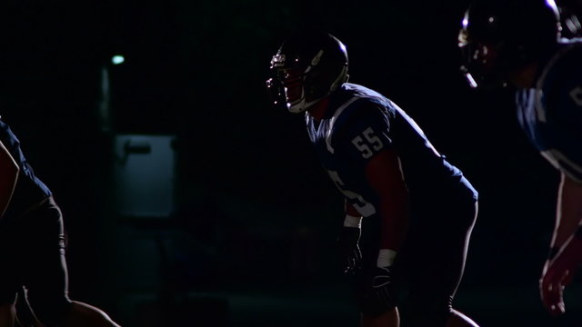 Three football defensive players lone up and get ready to blitz the quarterback