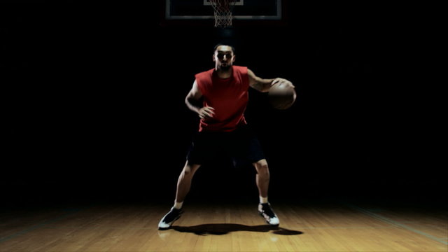 A solo basketball player does some dribbling moves in front of the camera
