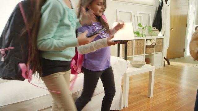 A Mother Hands Her Daughters Their Backpacks Before Leaving The House For School