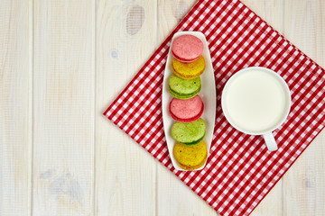 Empty plate with measure tape, macarons and milk. Diet food on w