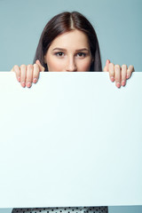 Fototapeta premium Beautiful woman standing behind, holding white blank advertising