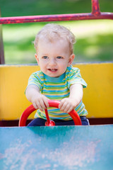 Fototapeta na wymiar Baby boy driving a toy car at the playground