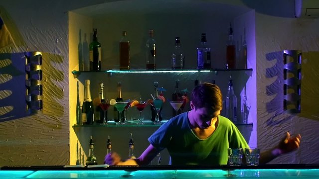 Young Bartender Making Tricks With Two Glasses And Bottle