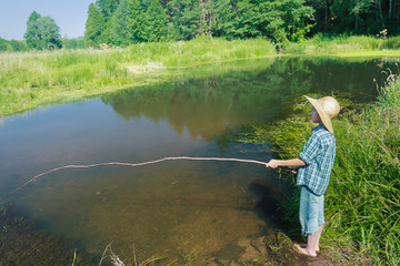 Barefoot fishing boy standing in transparent brownish waterbody 
