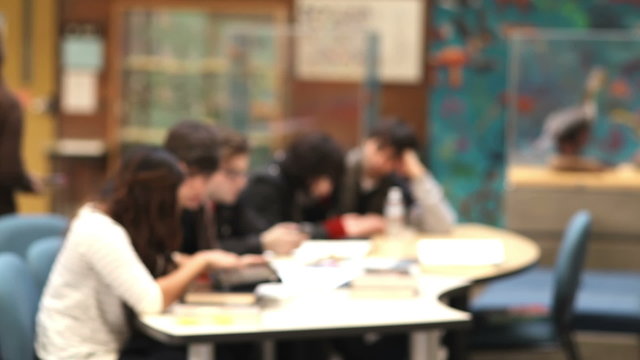 Wide shot of a group of students studying an experiment during class