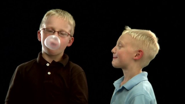 Two young blond boys pop bubblegum bubbles