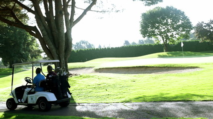 Golfing buddies ride in a golf cart together. 
