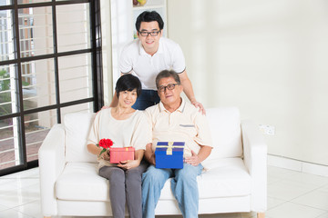 asian man giving present to father and mother