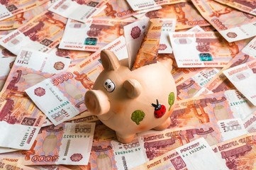 Piggy bank in a pile of russian five thousand banknotes