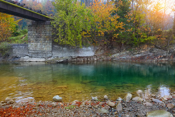 mountain river and railway bridge in autumn at sunset