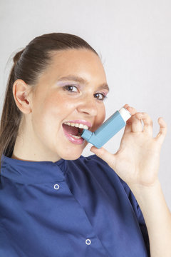 Pretty woman, nurse, using asthma inhaler