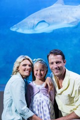 Happy family looking at camera beside the fish tank