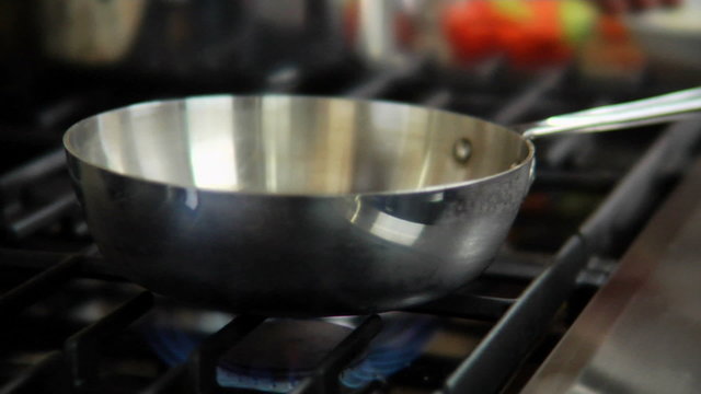 Close up of a pan being heated up over a stove