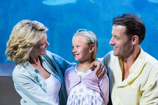Happy family standing beside the fish tank