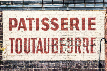 Old abandoned french bakery shop sign on a  brick wall 