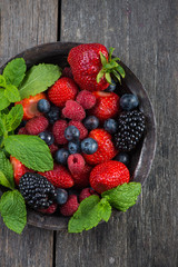 Fresh summer berries with mint in rustic bowl