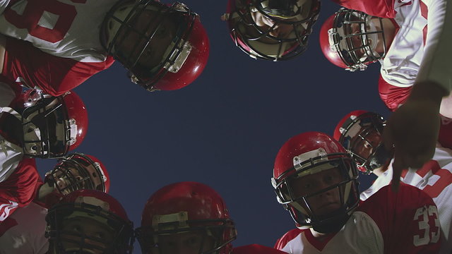 Football players in the huddle receiving the play form the quarterback
