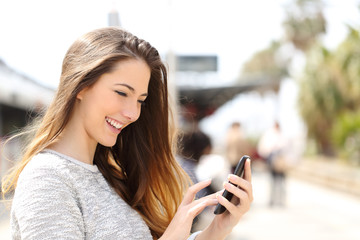 Girl texting on a smart phone in a train station