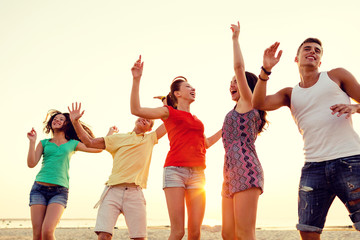 Fototapeta premium smiling friends dancing on summer beach