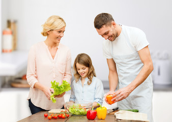 Obraz na płótnie Canvas happy family cooking vegetable salad for dinner