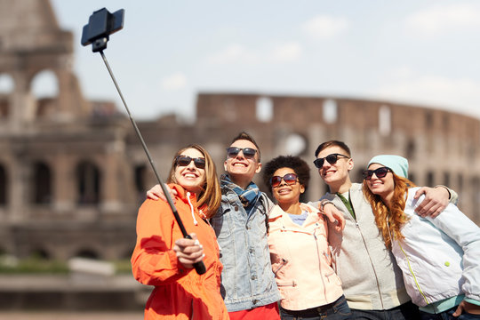 happy friends with smartphone selfie stick