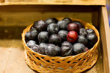ripe plums in basket at farm or food market
