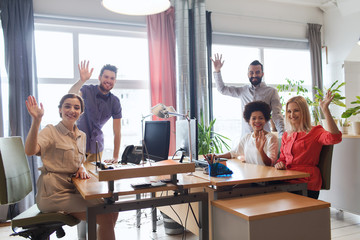 happy creative team waving hands in office