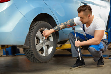 Fototapeta na wymiar Car Mechanic Changing Tire in Professional Car Repair Service