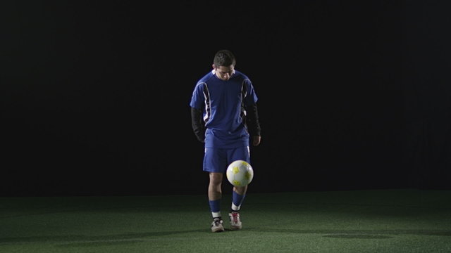 Soccer player shows some skill while juggling a soccer ball on black
