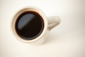 White cup full of black coffee stands on the table