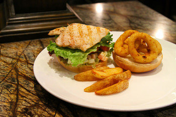 Delicious steak burger served with onion rings and fries.