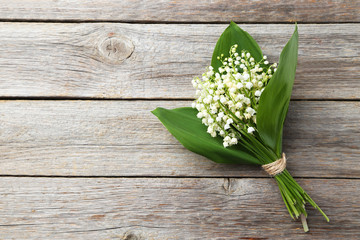 Lily of the Valley with leaves on grey wooden background - obrazy, fototapety, plakaty