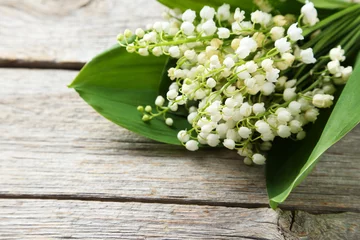 Rolgordijnen Lily of the Valley with leaves on grey wooden background © 5second
